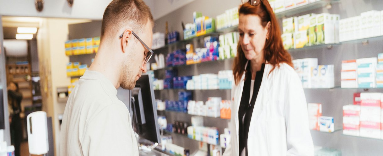 Person lässt sich in einer Apotheke zu Medikamenten beraten.