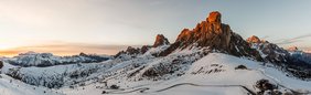 Panoramaaufnahme einer verschneiten Berglandschaft bei Sonnenuntergang.