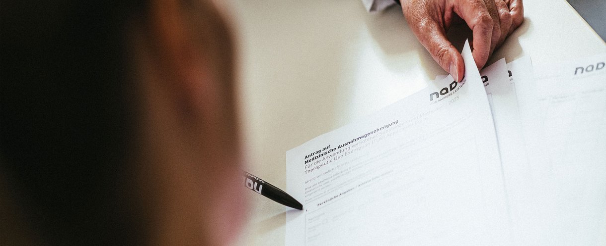 Person erhält Informationen zu einem Antrag auf Medizinische Ausnahmegenehmigung (TUE) anhand eines NADA-Formulars.