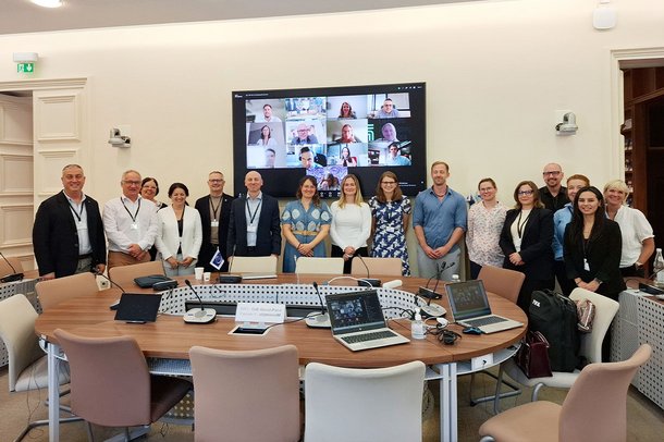 Teilnehmende des Treffens der Advisory Group on Science in Paris vor einem großen Bildschirm mit zugeschalteten Online-Teilnehmenden.