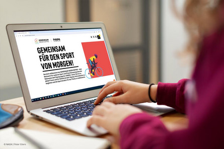 Eine Person sitzt an einem Laptop und schaut sich die neue Website von GEMEINSAM GEGEN DOPING an.