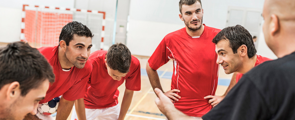 Spieler stehen im Kreis und besprechen sich mit Trainer